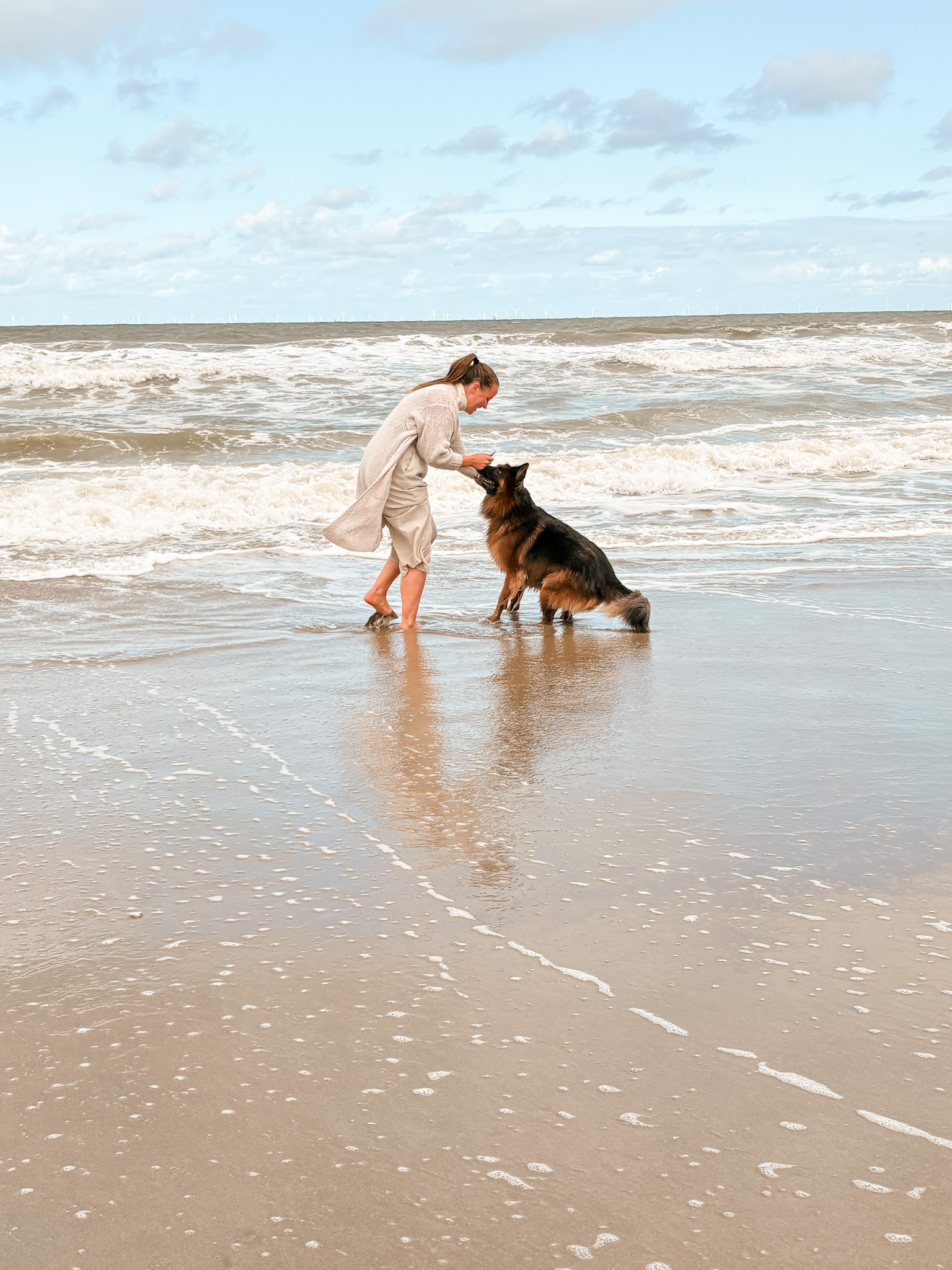 Sophie en Louie spelen samen aan de waterlijn op het strand.
